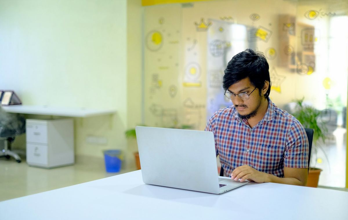 A young professional working on a laptop in a bright startup office